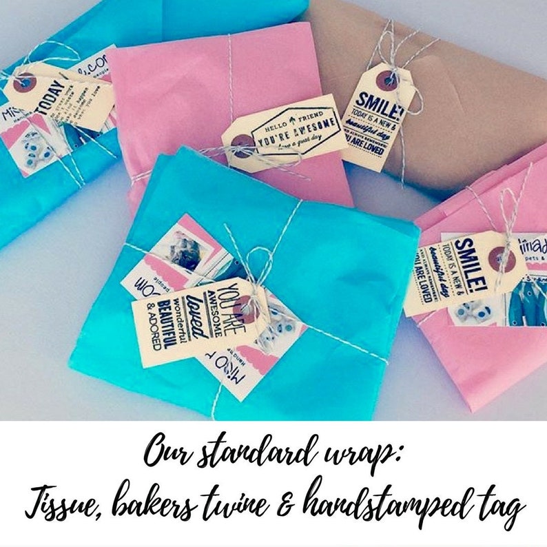 Puede incluir: Cuatro regalos envueltos en papel de seda, atados con cuerda y decorados con etiquetas estampadas a mano. Las etiquetas tienen mensajes positivos como "You are Awesome" y "Smile! Today is a new & beautiful day".