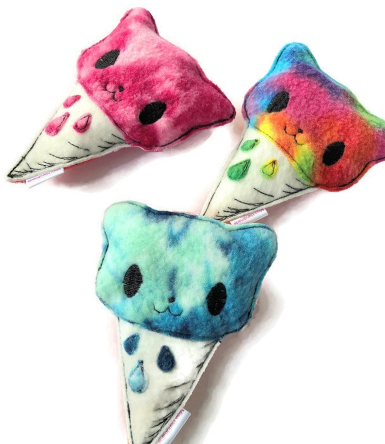 Puede incluir: Tres juguetes de peluche en forma de cono de helado con tela de te&ntilde;ido anudado y caras bordadas. Los conos de helado son rosa, azul y arco&iacute;ris.