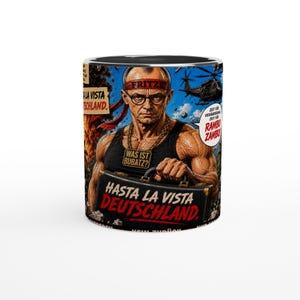 Puede incluir: Una taza de cerámica con una ilustración gráfica de una persona musculosa con una cinta roja en la cabeza que dice FRITZE, gafas y una camiseta negra con una etiqueta que dice WAS IST BUBATZ. El texto dice HASTA LA VISTA DEUTSCHLAND y RAMBO ZAMBO.