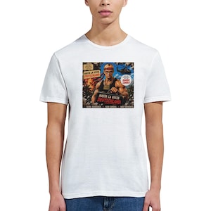 Puede incluir: Una camiseta blanca de manga corta con un estampado gráfico de una figura musculosa con camiseta de tirantes negra y cinta roja en la cabeza. El estampado incluye el texto "HASTA LA VISTA DEUTSCHLAND," "RAMBO ZAMBO," y "KEINE AUSREDEN. KEIN ZURÜCK. NUR VORWÄRTS."