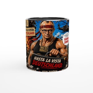 Puede incluir: Una taza de cerámica con una ilustración gráfica de una figura musculosa con gafas, una cinta roja en la cabeza con la etiqueta FRITZE y una camiseta sin mangas negra. El diseño incluye un maletín con el texto HASTA LA VISTA DEUTSCHLAND y un collar con el texto WAS IST BUBATZ?