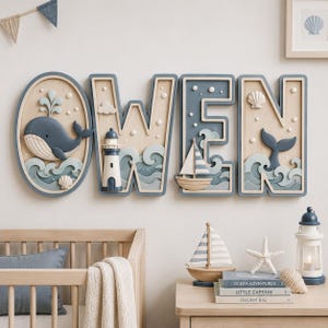 Könnte beinhalten: Ein hölzernes Wandschild mit dem Namen OWEN, das mit geschichteten nautischen Motiven gestaltet ist. Der Buchstabe O ist ein Oval mit Wal und Wellen. Das W enthält einen Leuchtturm. Das E zeigt ein Segelboot. Das N zeigt eine Walschwanzflosse.
