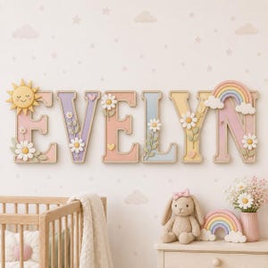 May include: A wall-mounted wooden name sign spelling EVELYN in large, pastel-coloured block letters. Each letter is decorated with 3D floral accents, small hearts, a smiling yellow sun on the first letter, and a rainbow with clouds on the last letter.