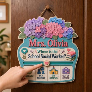 May include: A decorative wall sign shaped like a jar with purple and pink hydrangea flowers on top. It features the text Mrs. Olivia, Where is the School Social Worker? and a sliding heart marker to indicate status options: Available, In a Meeting, On Campus, or Out of Office.