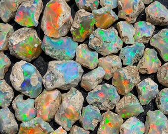 May include: A collection of raw, unpolished opal stones featuring a milky white base with vibrant flashes of neon green, orange, and blue color play. Each stone retains its natural, irregular rock matrix texture and jagged edges.