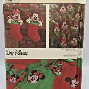 May include: A Simplicity Crafts sewing pattern envelope, number 8292, featuring Walt Disney Mickey Mouse and Minnie Mouse Christmas decorations. The package displays illustrations of fabric stockings, tree ornaments, and a tree skirt with character faces.