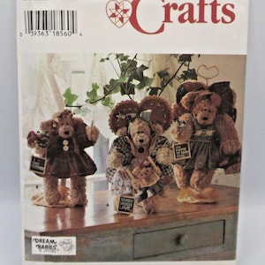 May include: A Simplicity Crafts sewing pattern envelope, number 7000, featuring illustrations of three brown teddy bears dressed in various outfits. The bears hold small signs with text including I Love You, Beary Much Love, and My Name Is Baby Rose.
