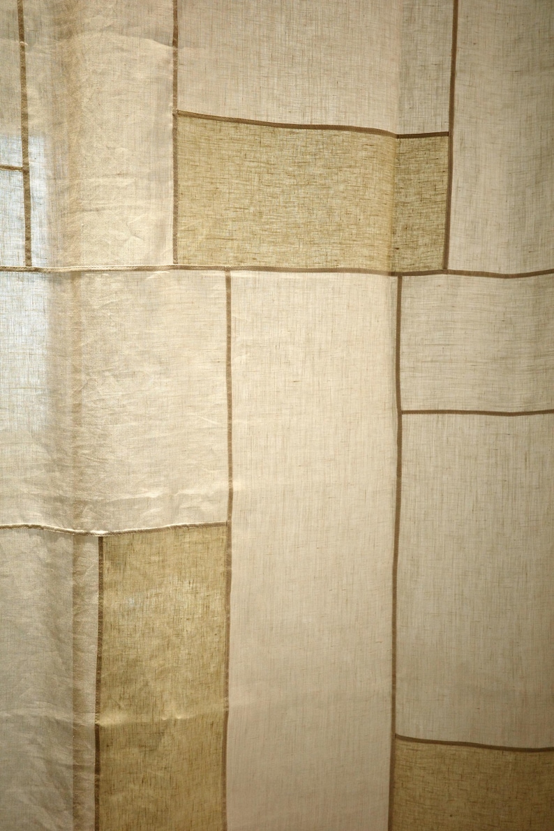 Puede incluir: Un panel de cortina con un dise&ntilde;o de patchwork de segmentos de tela rectangulares en varios tonos de beige y bronceado. La tela tiene una textura tejida visible, y cada secci&oacute;n rectangular est&aacute; separada por finas l&iacute;neas verticales y horizontales marrones.