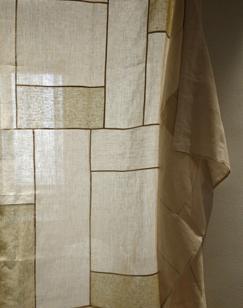 Puede incluir: Un panel de cortina semitransparente con un dise&ntilde;o de patchwork de segmentos rectangulares en varios tonos de beige, crema y bronceado claro. La tela tiene una textura tejida visible y los segmentos est&aacute;n unidos por finas costuras lineales de color marr&oacute;n oscuro.