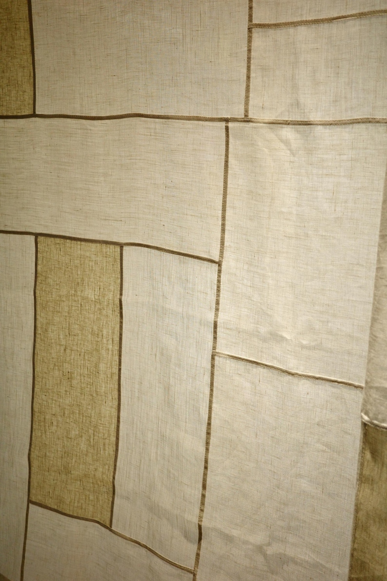 Puede incluir: Un panel textil con un dise&ntilde;o de patchwork de segmentos rectangulares en varios tonos de beige y bronceado. La tela tiene una textura tejida visible y cada secci&oacute;n est&aacute; unida por costuras finas de color marr&oacute;n oscuro que crean un patr&oacute;n de rejilla.