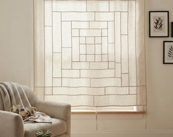 Könnte beinhalten: Ein beigefarbener Fenstervorhang aus Leinen mit einem geometrischen Gittermuster aus genähten Linien, die ein konzentrisches Quadratdesign bilden. Der Vorhang hängt flach vor dem Fenster und zeigt eine leichte, halbtransparente Textur.