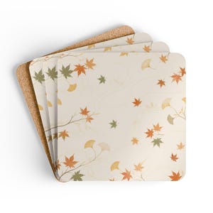 May include: A set of four square coasters with rounded corners, featuring a cream-colored surface decorated with a pattern of orange and green maple leaves and yellow ginkgo leaves, with a natural brown cork backing visible on the edges.