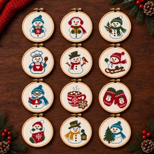 May include: Twelve circular wooden embroidery hoops containing cross-stitch patterns of snowmen and winter motifs. Designs include snowmen with hats, scarves, mugs, mittens, a stocking, and a Christmas tree, all stitched on white fabric.