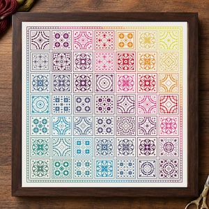 May include: A square cross-stitch embroidery piece framed in dark wood, featuring a grid of forty-nine individual geometric patterns arranged in a rainbow color gradient, transitioning from purple and blue to green, yellow, orange, and pink.