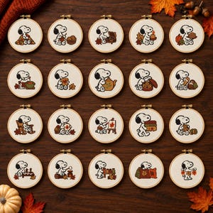 May include: A collection of twenty circular wooden embroidery hoops, each containing a white fabric panel with a cross-stitch design of Snoopy engaged in various autumn-themed activities, including holding pumpkins, leaves, and warm beverages.