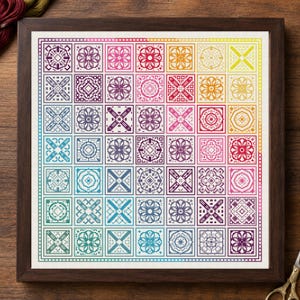 May include: A framed cross-stitch sampler featuring a grid of forty-nine square blocks, each containing a unique geometric pattern. The colors transition in a rainbow gradient from purple and blue to green, yellow, orange, and pink.
