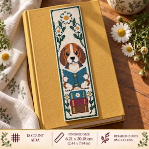 May include: A rectangular cross-stitch bookmark featuring a brown and white beagle dog reading a blue book, stacked atop two other books. The design is framed by green stems and white daisy flowers, measuring 2.44 by 7.94 inches on 18 count Aida.