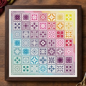 May include: A square cross-stitch embroidery piece framed in dark wood, featuring a grid of forty-nine individual geometric patterns arranged in a rainbow color gradient, transitioning from purple and blue to yellow and red.
