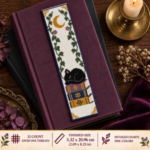 Op de afbeelding: Een rechthoekige kruissteek boekenlegger met een zwarte kat die slaapt op een stapel van drie kleurrijke boeken. Het ontwerp bevat groene klimopranken, een gele maansikkel en kleine paarse bloemen. De afgewerkte maat is 5,32 bij 20,96 cm.