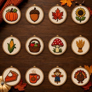 Könnte beinhalten: Zwölf runde Stickrahmen mit Kreuzstichmotiven zum Thema Herbst, darunter ein Kürbis, eine Eichel, ein Ahornblatt, eine Sonnenblume, Mais, ein Apfelkorb, ein Pilz, eine Weizengarbe, ein Stück Kürbiskuchen, eine Tasse, eine Vogelscheuche und ein Truthahn.