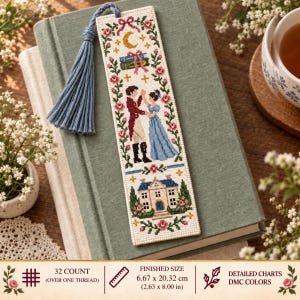 Op de afbeelding: Een rechthoekige kruissteek boekenlegger met een dansend paar, een huis en bloemenranden. Het heeft een blauw kwastje en meet 6,67 bij 20,32 cm. Het ontwerp bevat een halve maan, boeken en roze rozen op een witte stoffen ondergrond.