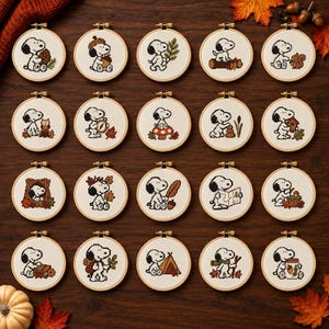 Pode incluir: Uma coleção de vinte bastidores de bordado circulares de madeira, cada um contendo um design em ponto cruz da personagem Snoopy em várias atividades com tema de outono, incluindo bolotas, folhas e abóboras em tecido branco.