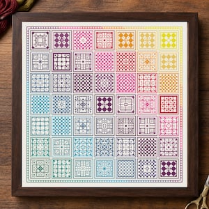 May include: A framed cross-stitch sampler featuring a grid of forty-nine square blocks, each containing a unique geometric pattern. The design displays a vibrant color gradient transitioning from purple and blue to pink, red, orange, and yellow.