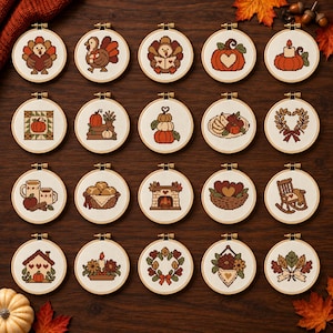 Op de afbeelding: Een verzameling van twintig ronde borduurringen met kruissteekontwerpen met herfstthema's, waaronder kalkoenen, pompoenen, herfstbladeren, kaarsen, een open haard, een schommelstoel en oogstmanden, allemaal gerangschikt in een rasterpatroon.