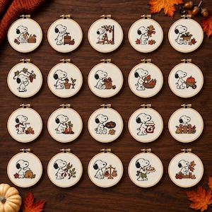 May include: Twenty circular embroidery hoops featuring cross-stitch designs of Snoopy engaged in various autumn harvest activities. Each hoop displays a unique scene with fall-themed elements like pumpkins, apples, leaves, and garden tools.