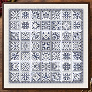May include: A square cross-stitch sampler featuring a grid of forty-nine individual blocks, each containing a unique dark blue geometric or floral pattern stitched onto a white fabric background, framed in a dark brown wooden border.