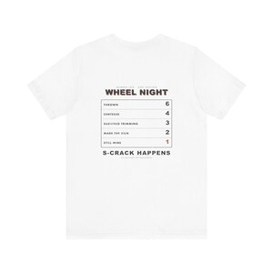 May include: A white short-sleeve t-shirt featuring a black graphic chart titled WHEEL NIGHT. The chart lists pottery steps: THROWN 6, CENTERED 4, SURVIVED TRIMMING 3, MADE THE KILN 2, and STILL MINE 1 in red. The text S-CRACK HAPPENS appears below.