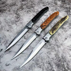 May include: Three folding knives with silver metal blades and bolsters. The first knife has a black handle, the second features a brown wood grain handle, and the third has a textured, cream-colored handle with dark brown markings.