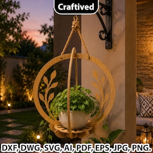 Op de afbeelding: Een ronde houten hangende plantenhouder met bladvormige uitsparingen, opgehangen aan een dik touw aan een zwarte metalen muurbeugel. Een witte keramische pot met een groene plant staat in het houten frame. Tekst leest Craftived.