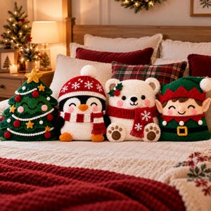 Könnte beinhalten: Vier gehäkelte Plüschkissen in Form eines Weihnachtsbaums, eines Pinguins mit roter Mütze und Schal, eines weißen Bären mit rotem Schal und eines Elfen. Jedes Plüschtier zeichnet sich durch detaillierte Nähte und festliche Motive aus.