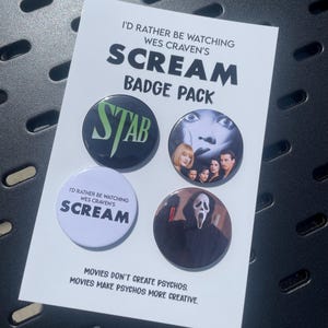 May include: A badge pack featuring four circular pins on a white display card. The card text reads I'D RATHER BE WATCHING WES CRAVEN'S SCREAM BADGE PACK and MOVIES DON'T CREATE PSYCHOS. MOVIES MAKE PSYCHOS MORE CREATIVE. Pins show STAB, movie cast, SCREAM, and Ghostface.