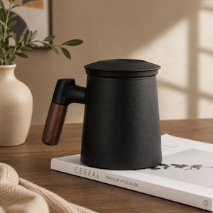 May include: A matte black ceramic mug with a cylindrical body and a matching lid. The mug features a distinct handle with a dark brown wood-grain finish. The surface of the mug has a textured, slightly granular appearance, providing a contrast to the smooth wooden handle.