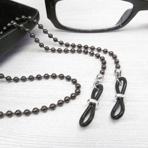 May include: A black beaded eyeglass chain with black rubber loops and silver clasps.