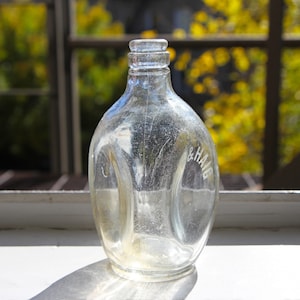 May include: A clear glass bottle with a textured surface. The bottle has a label that reads "& Haig".