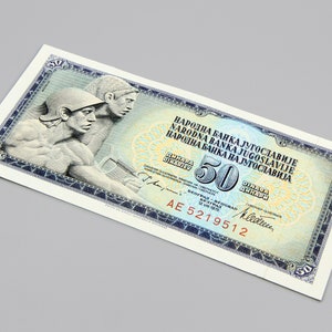 Puede incluir: Un billete de banco yugoslavo vintage de 50 dinares, con un diseño azul y blanco con el texto "NARODNA BANKA JUGOSLAVIJE" y un retrato de dos hombres con armadura romana.