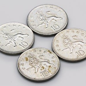 Może przedstawiać: Cztery srebrne monety 10 pensów, każda z motywem lwa i korony oraz napisem "TEN PENCE". Monety ułożone są w okrąg na jasnoszarym tle.