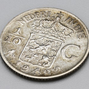 May include: Silver coin from the Netherlands Indies, dated 1942, with the inscription "NEDERL INDIE" and a depiction of a lion holding a sword.