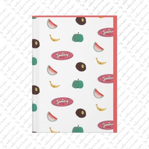 Puede incluir: Un cuaderno blanco con lomo y borde de color rojo coral que presenta un patrón repetitivo de rodajas de sandía, plátanos amarillos, manzanas verdes, formas circulares marrón oscuro y etiquetas ovaladas rosas con el texto Juicy.