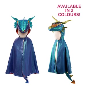 Peut inclure: Deux capes de dragon avec capuches, l'une bleu irisé et l'autre vert irisé. Les deux présentent des écailles texturées, des cornes et une queue. Le texte "AVAILABLE IN 2 COLOURS!" est affiché en rose au-dessus des capes sur des mannequins blancs.