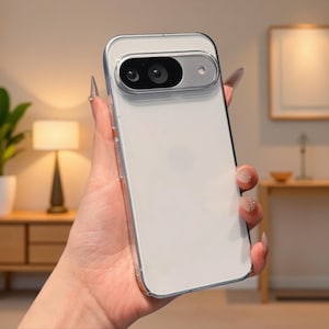 Könnte beinhalten: Eine transparente Schutzhülle für ein Smartphone mit einem erhöhten, rechteckigen Kameraausschnitt und einem metallisch silbernen Rand. Die Hülle hat eine glatte, glänzende Oberfläche, durch die das Gerät darunter sichtbar ist.