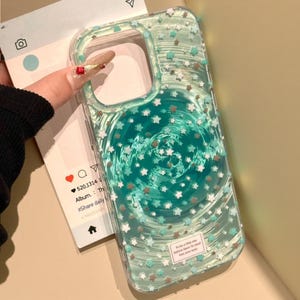 May include: A clear phone case featuring a swirling teal and green background pattern with scattered small white and light blue stars. A small rectangular white label at the bottom contains the text: To be a little star before dawn To steal kiss your eyes.