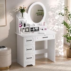 May include: A white vanity table featuring an oval mirror, three stacked drawers on the left, and one wide drawer under the tabletop. The unit includes open shelving for storage, black drawer pulls, and a smooth finish for organizing cosmetics.