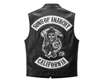 Könnte beinhalten: Eine schwarze Lederweste mit einem großen Rückenaufnäher, der einen Sensenmann mit Gewehr und ein Anarchie-Symbol zeigt. Der Schriftzug SONS OF ANARCHY ist darüber gebogen, CALIFORNIA steht darunter und ein kleiner MC-Aufnäher ist seitlich.