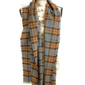 May include: A brown and gray plaid scarf with fringed edges. The scarf is draped over a mannequin.