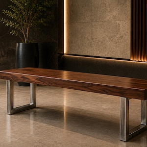 Peut inclure: Un banc rectangulaire doté d'une assise épaisse en bois brun foncé avec un motif de grain naturel visible. L'assise est soutenue par deux pieds robustes en métal brossé en forme de U qui offrent une base stable au meuble.