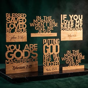 May include: A collection of six light brown wooden signs with laser-cut lettering featuring religious quotes including Blessed Saved Loved By Jesus John 3:16, In The Morning When I Rise Give Me Jesus, If You Love Me Keep My Commands John 14:15, You Are God's Masterpiece Ephesians 2:10, Putting God First Will Help You Succeed Psalm 16:8.